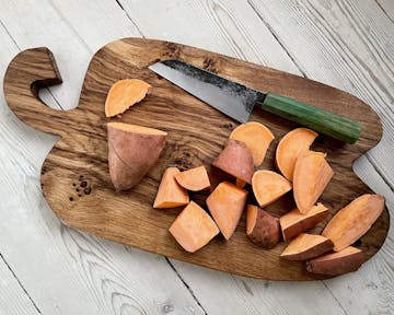 Chopping board with sweet potato and knife