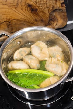 wonton cooking in soup in saucepan