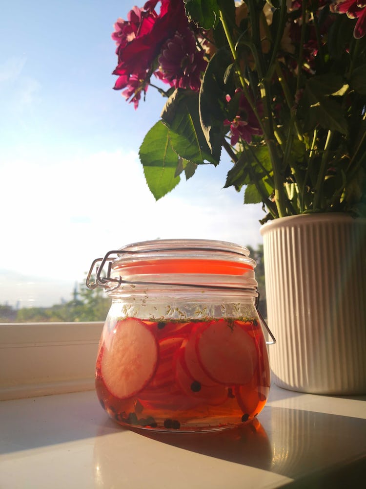 clear jar of radish pickles sitting on the window sill