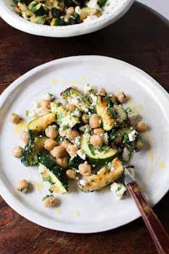 courgettes, chickpeas and feta on a white plate with a fork