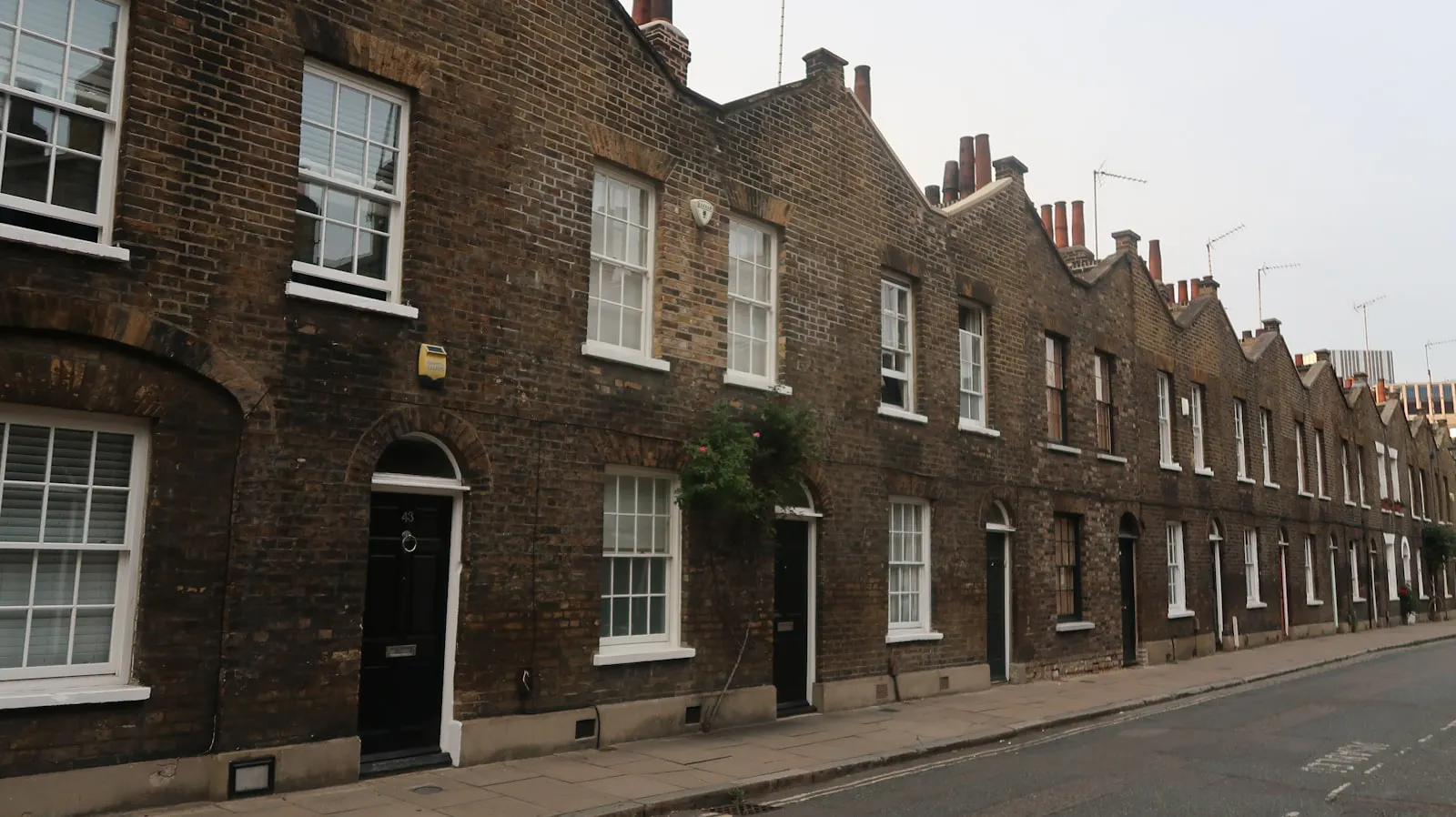 A row of UK brick terraced houses lining a residential street
