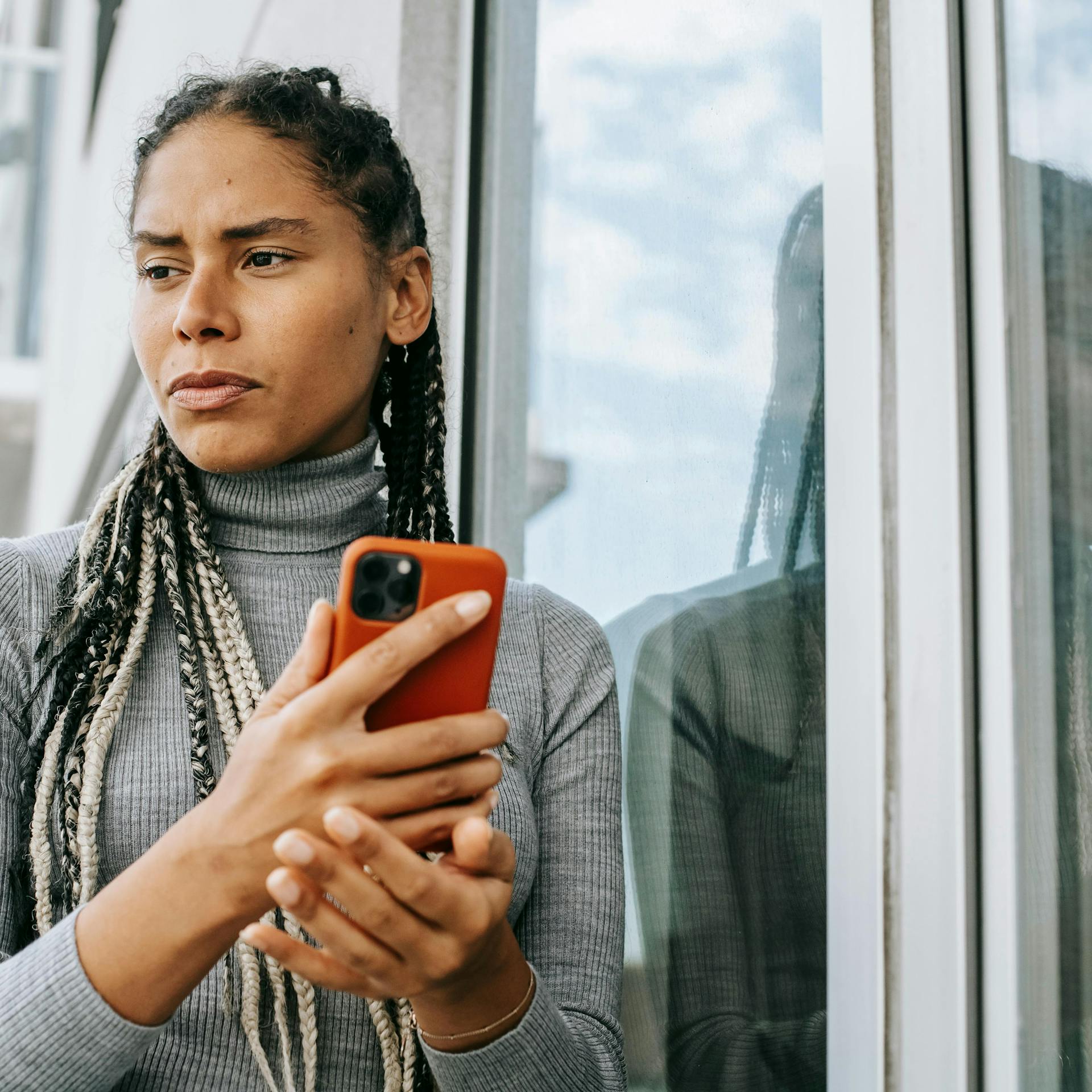 Imagem de uma mulher segurando um celular com uma capinha vermelha