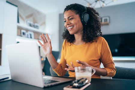 Mulher sorridente utilizando notebook em video-chamada