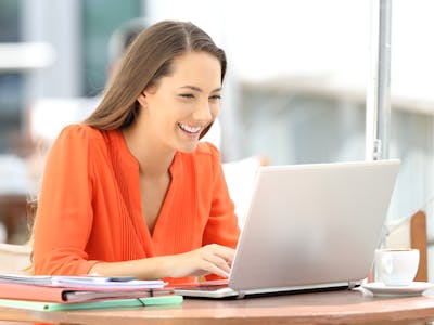 Mulher sorrindo e utilizando notebook conectado à Oi Fibra