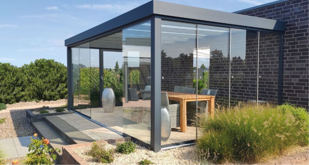 pergola with glass sides on a marble patio with a dining set