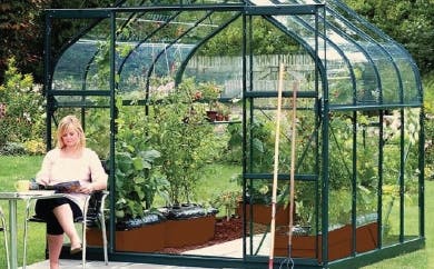 Woman sitting outside curved eave green greenhouse