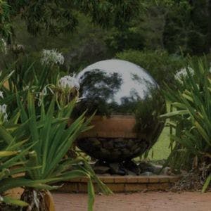 Modern round stainless steel water feature ball in garden setting