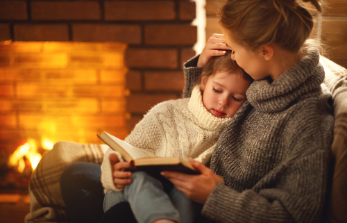 Parent and child reading in front of heater with warm glow