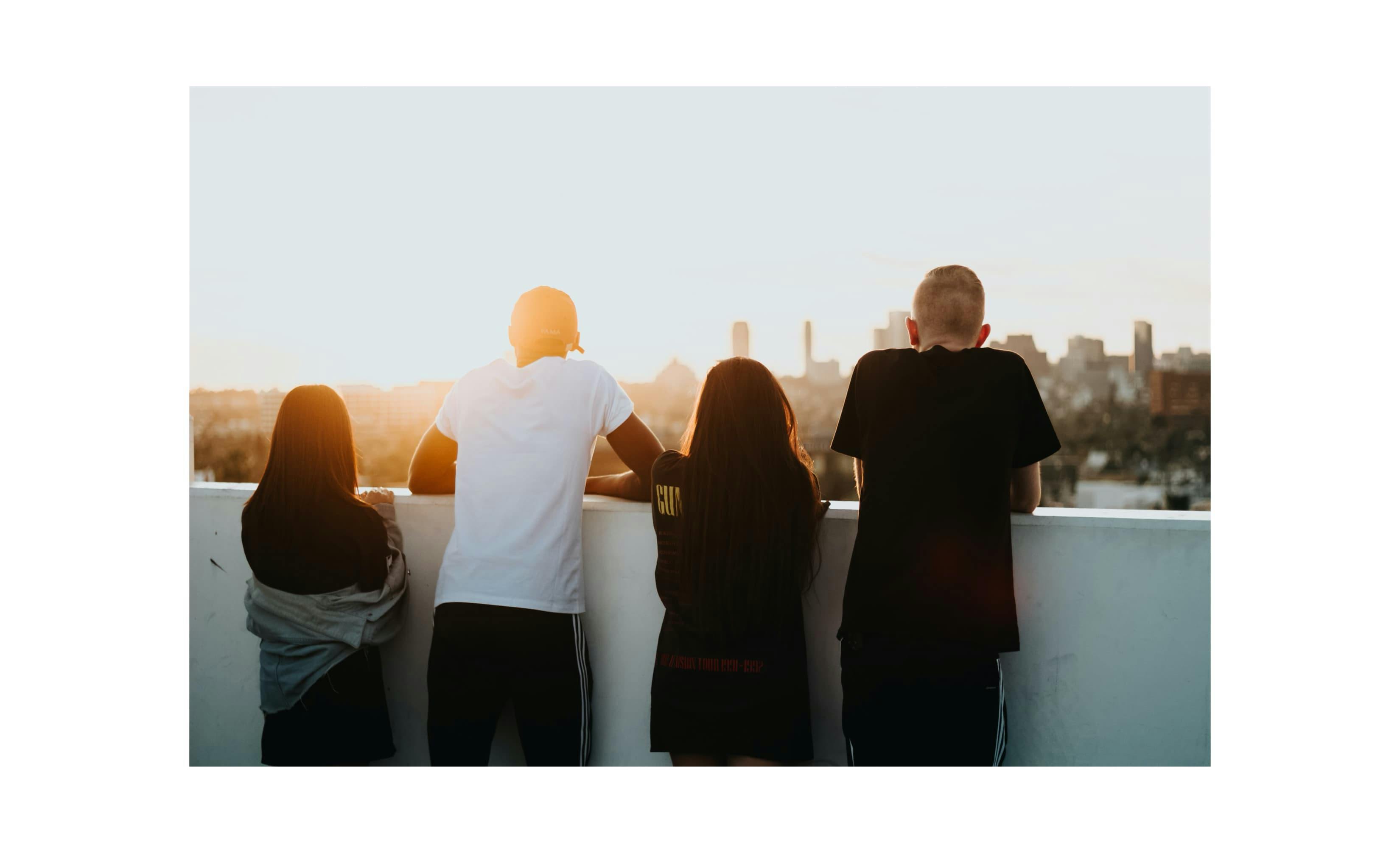 Four young people staring at sunset from a rooftop
