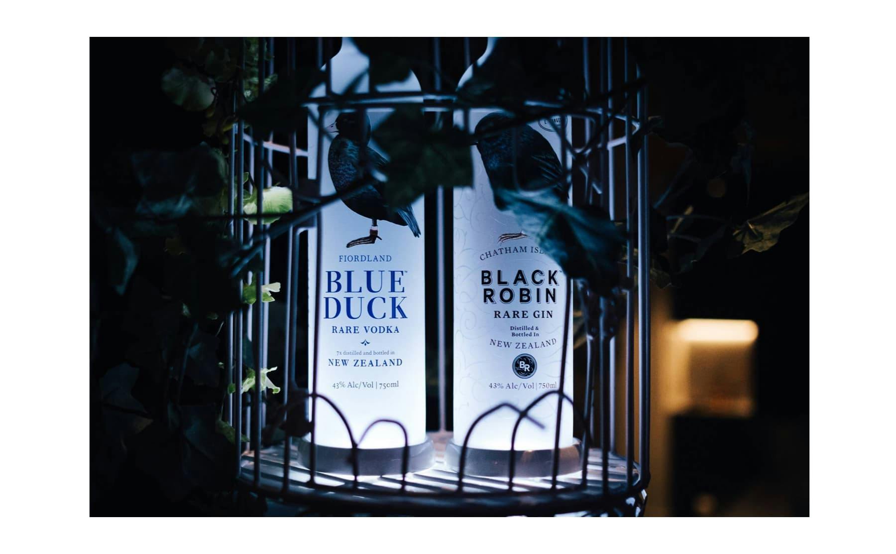 Blue Duck Vodka and Black Robin Gin bottles in birdcage display