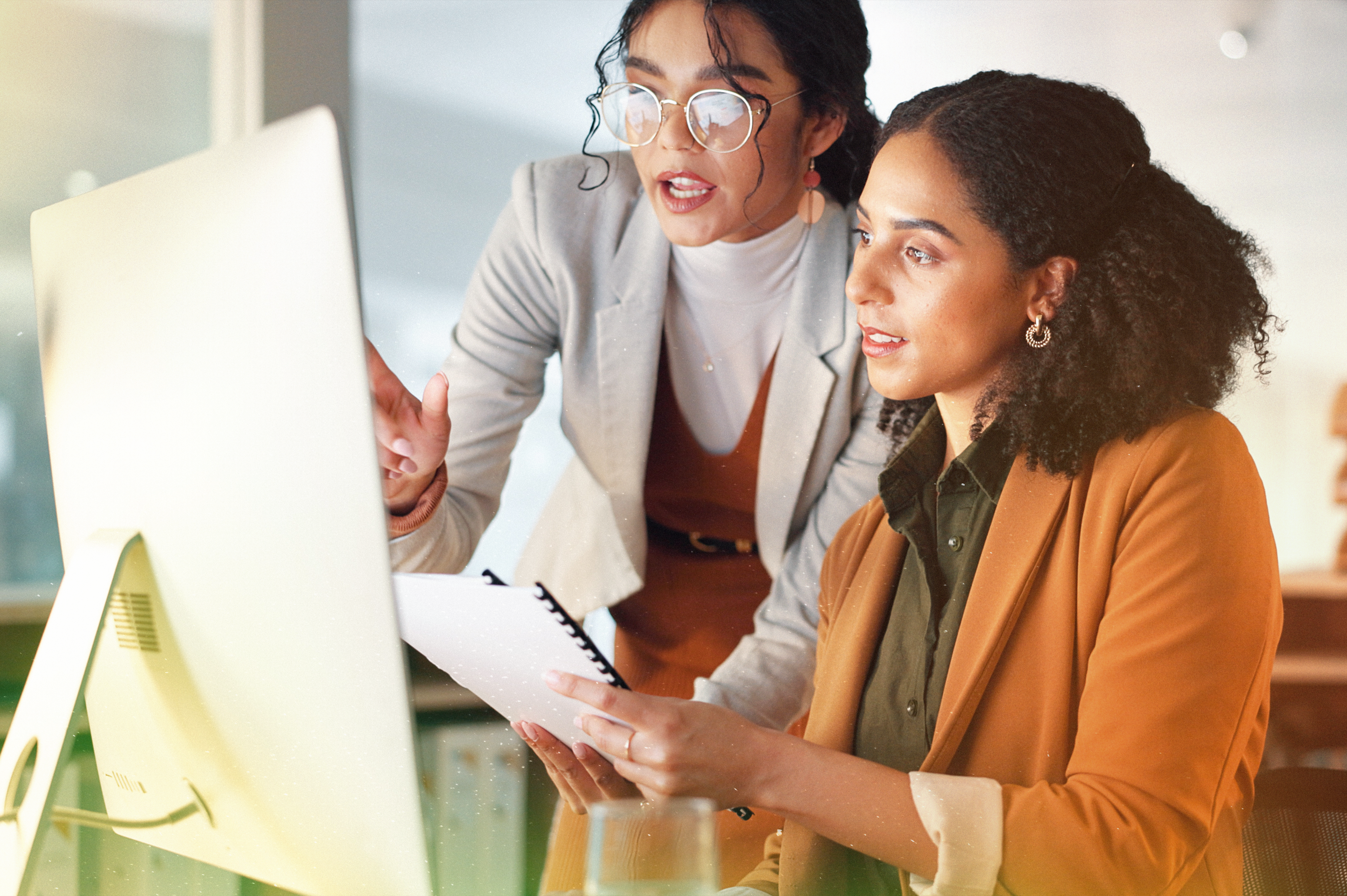 two women speaking in front of computer