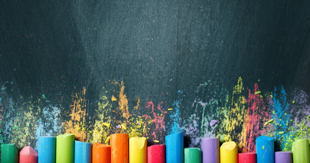 Photo of different colored chalk pieces on a chalkboard background
