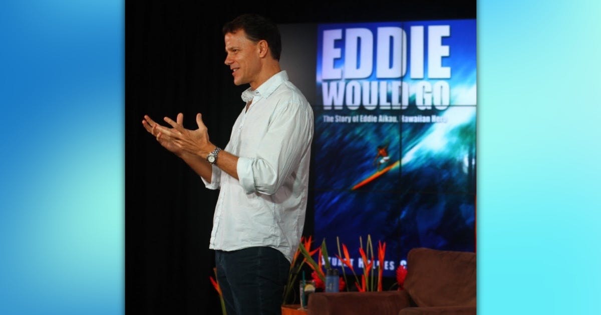 Photo of Stuart Coleman in front of a graphic of his book "Eddie Would Go"