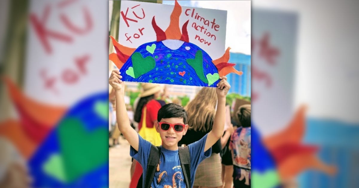 Photo of a child at a rally holding a sign in support of climate action