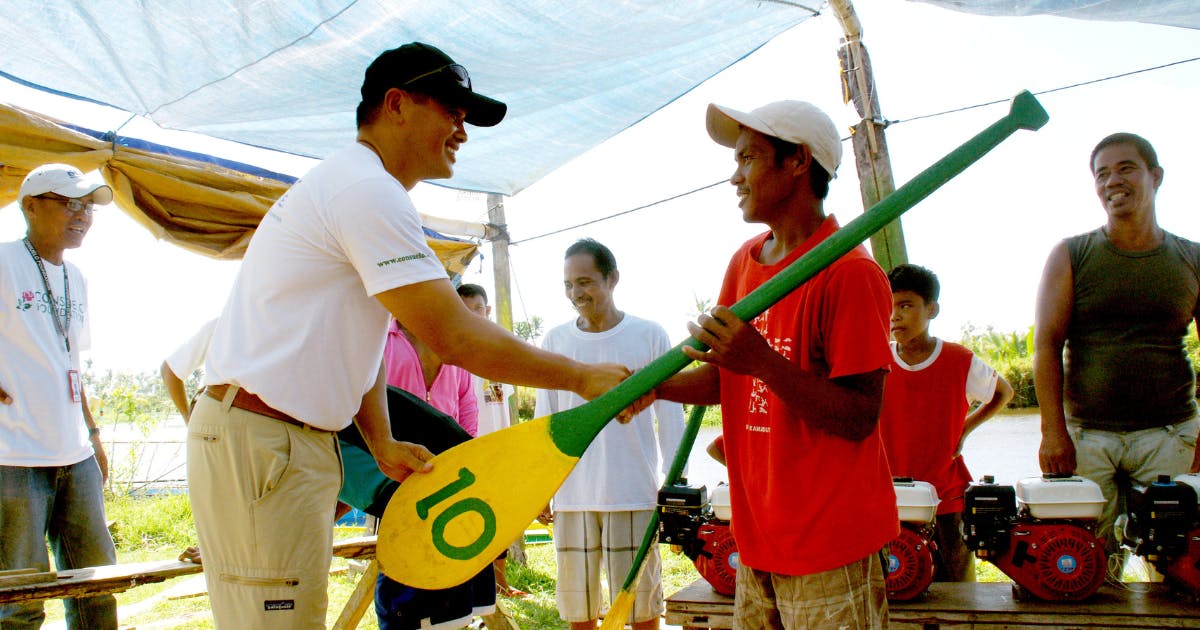 Photo of AJ handing a paddle to a fisherman