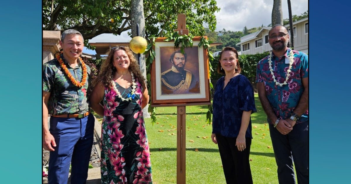 Photo of four Queen's Health Systems staff members standing beside a portrait of one of the hospital's founders, King Kamehameha IV