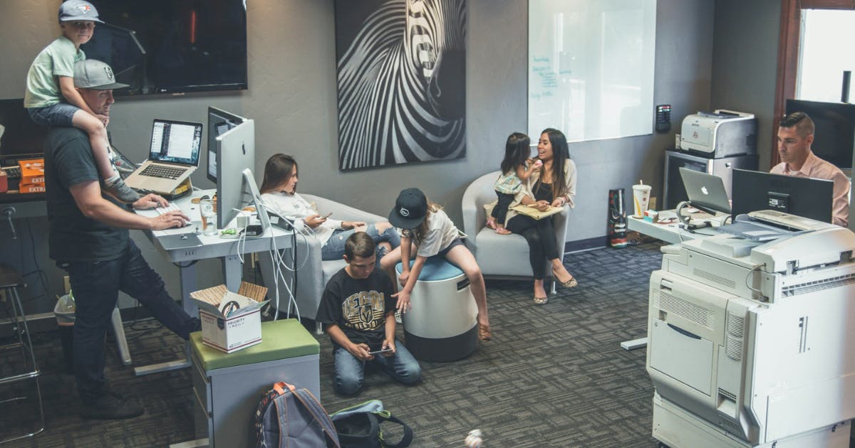 Photo of an open office space with people who have brought their children to work