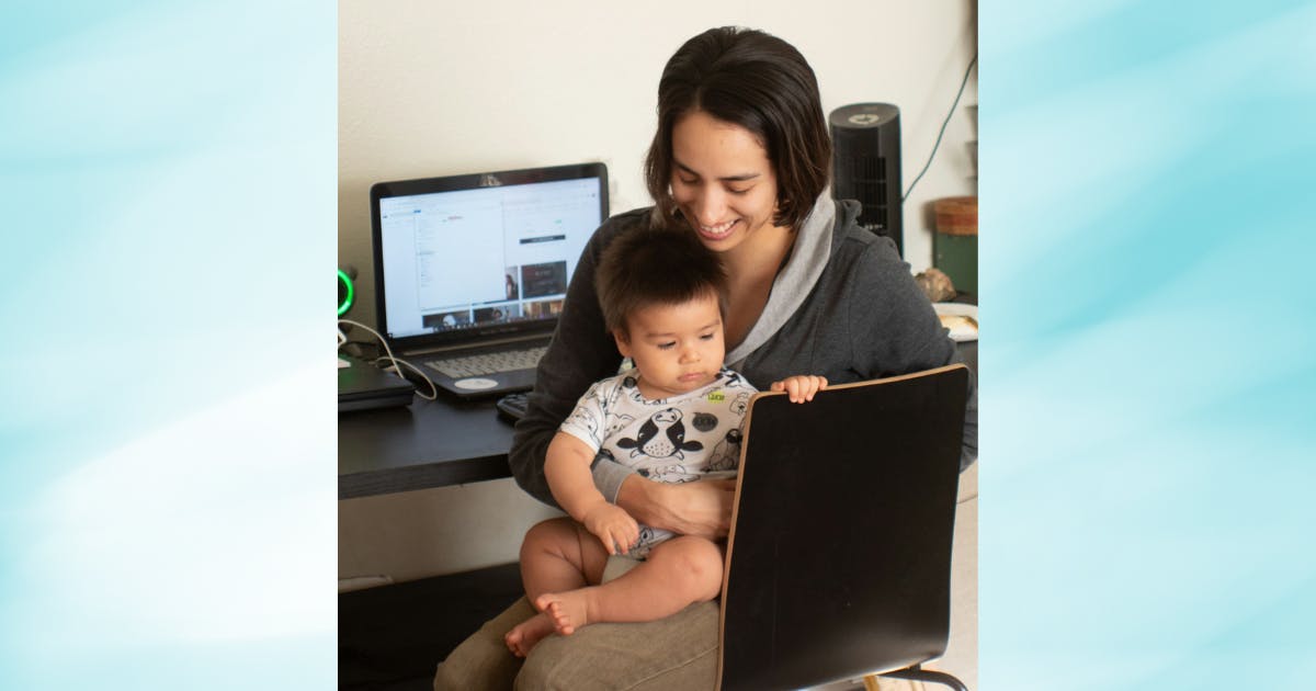 Photo of a mom and infant at a computer desk.