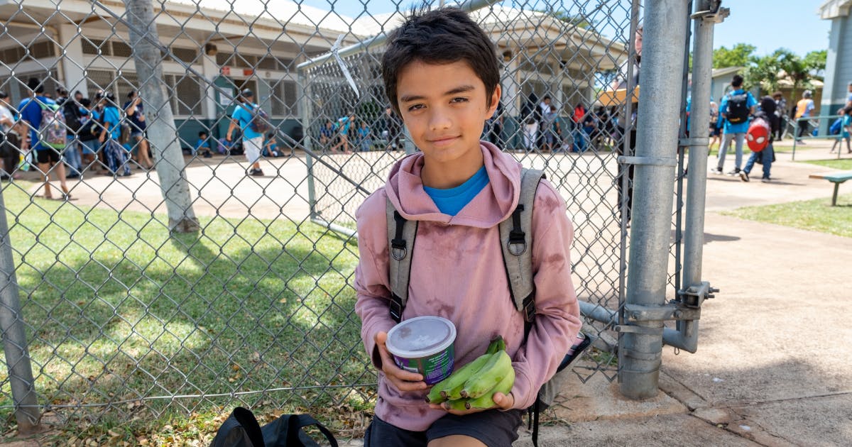 Photo of a school-age child holding food and produce