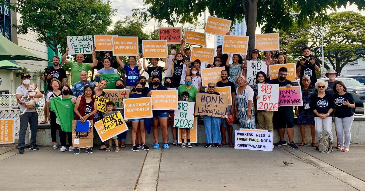 A group of living wage supporters wave signs at a rally in Honolulu.