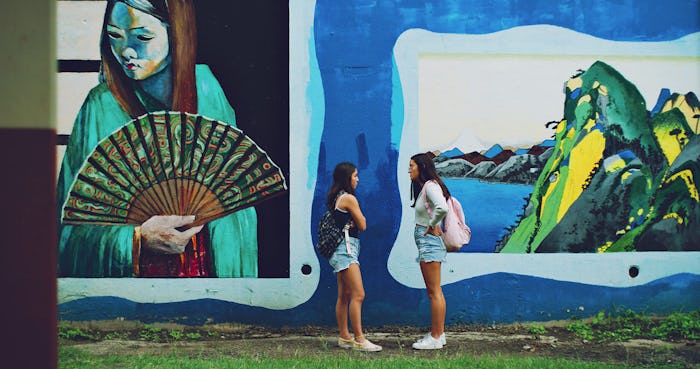 Photo of two students talking to each other in front of a mural