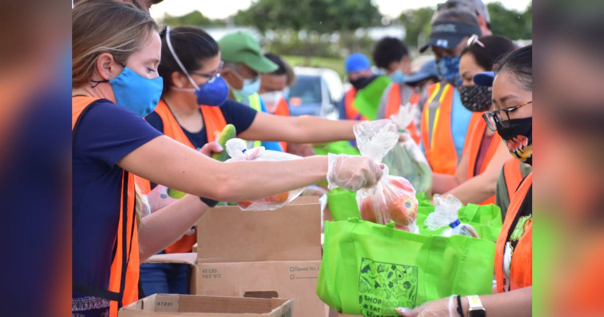 Photo of a line of Hawai‘i Foodbank volunteers preparing bags of food for distribution