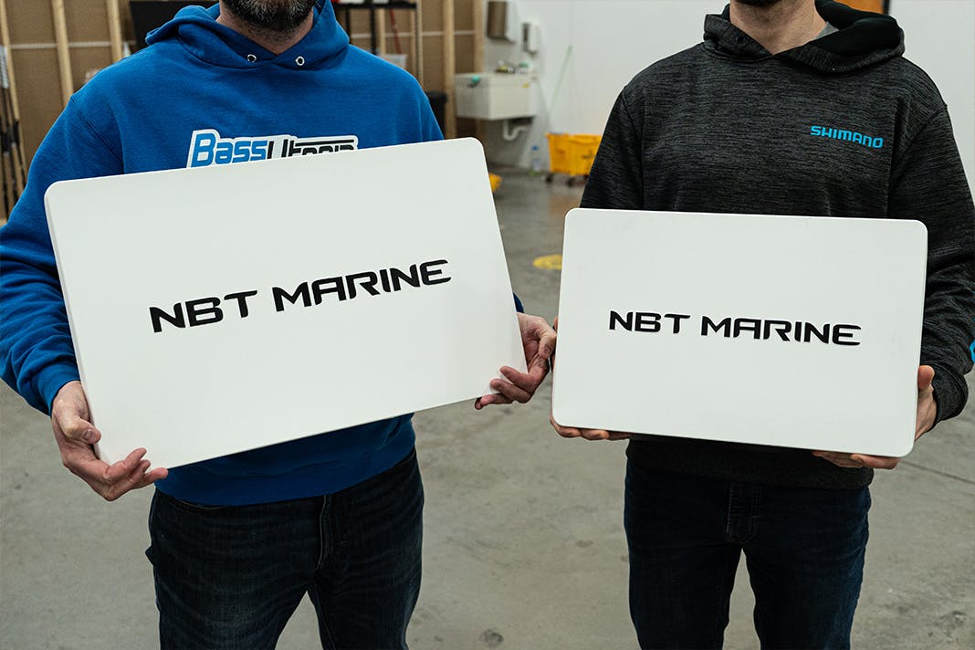 Two people holding one NBT screen each; 22" on the left and 16" on the right