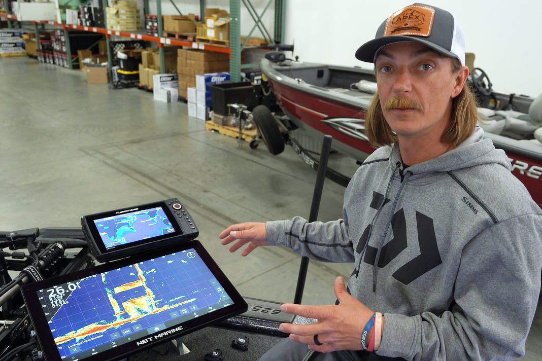 Seth Feider kneeling on his boat next to an NBT Marine screen