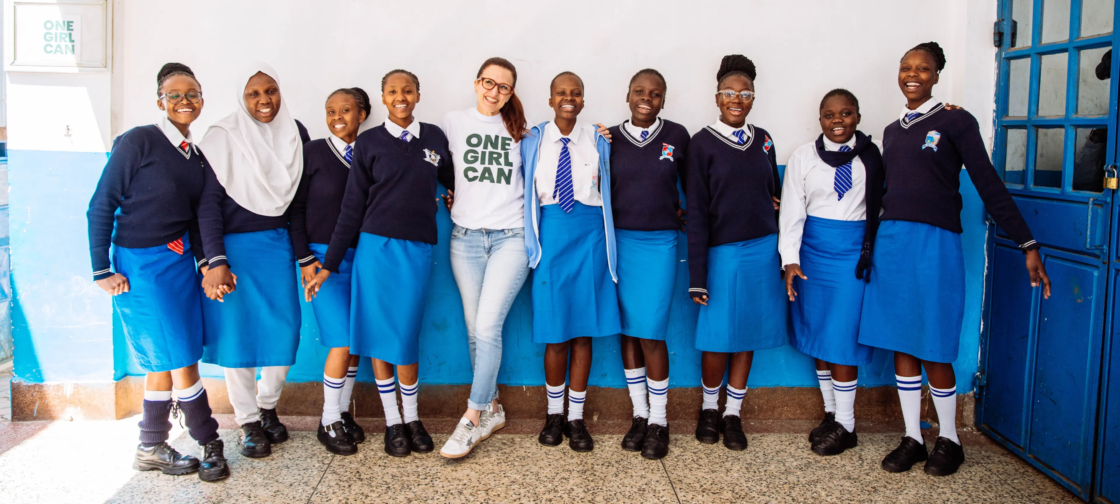 A One Girl Can team member standing with a line of students outside their school in Kenya