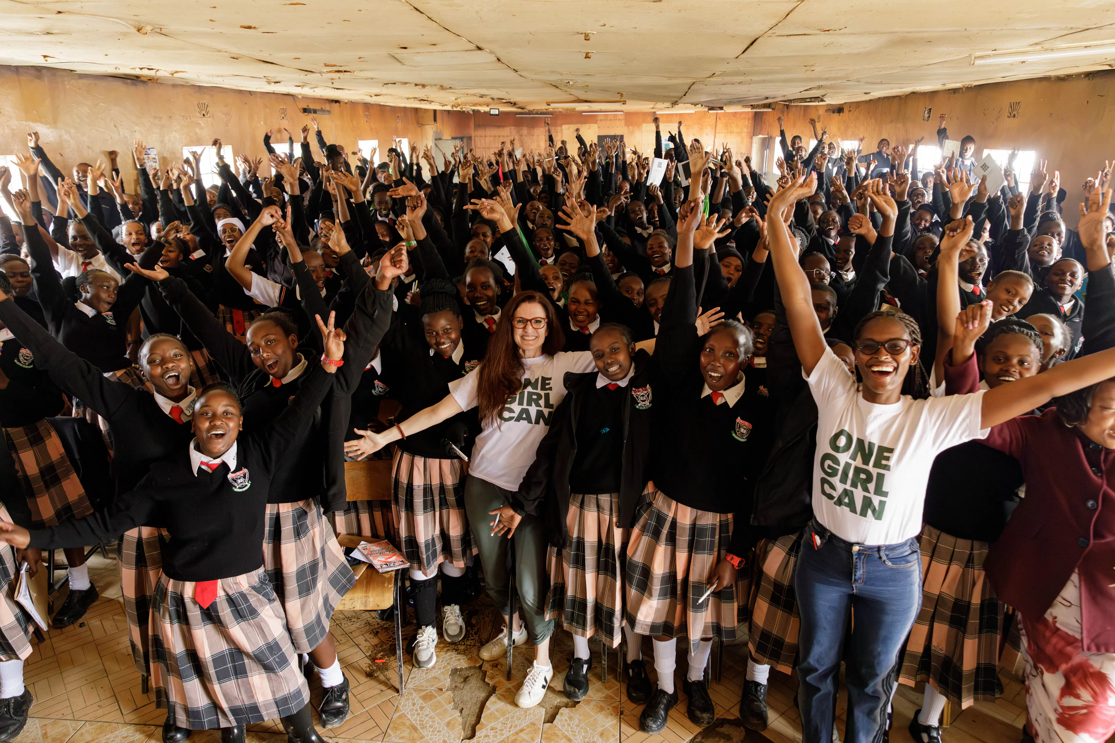 A school hall full of students cheering alongside One Girl Can staff
