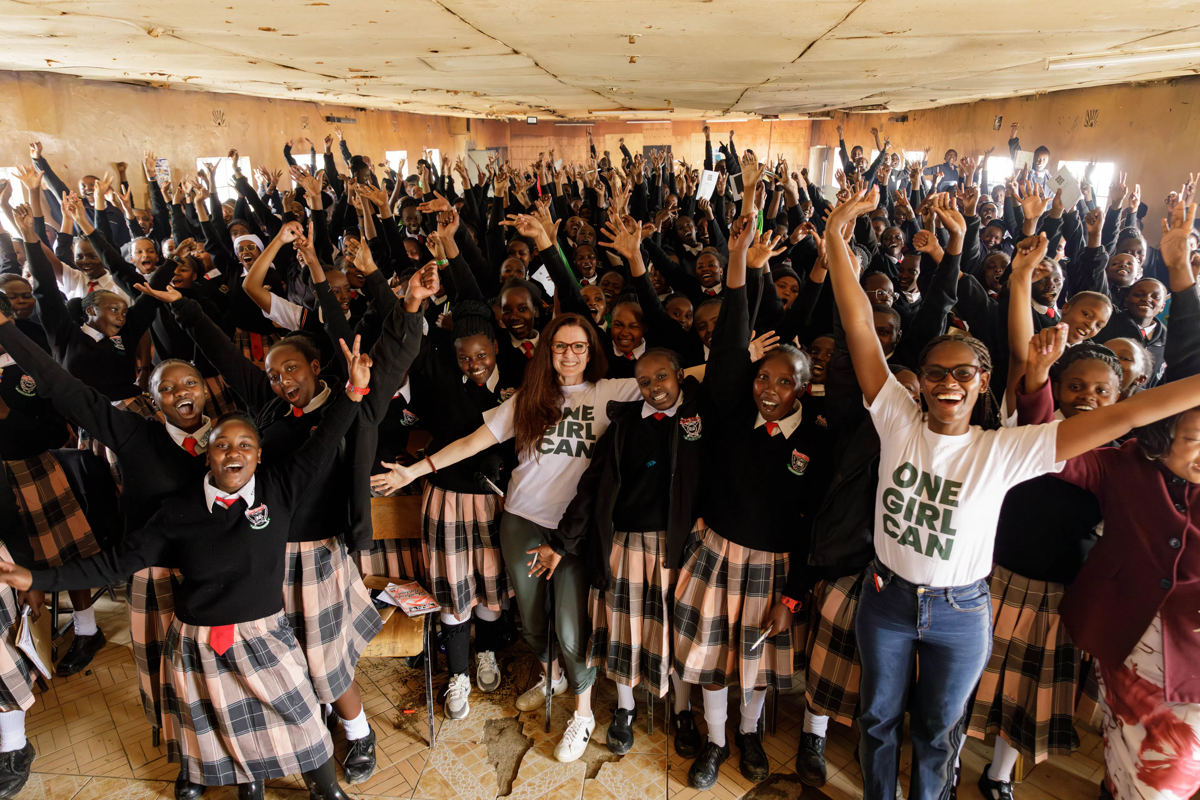 A school hall full of students cheering alongside One Girl Can staff