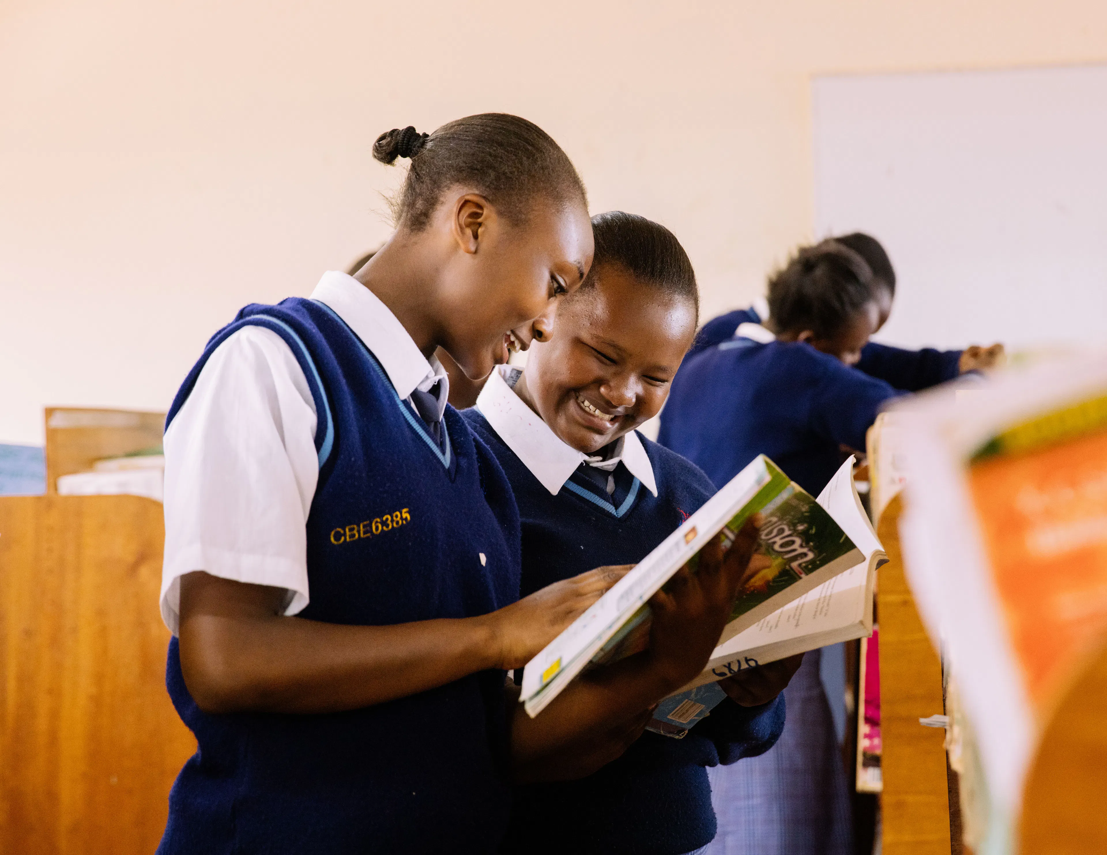 Two students in navy uniforms reading a textbook together
