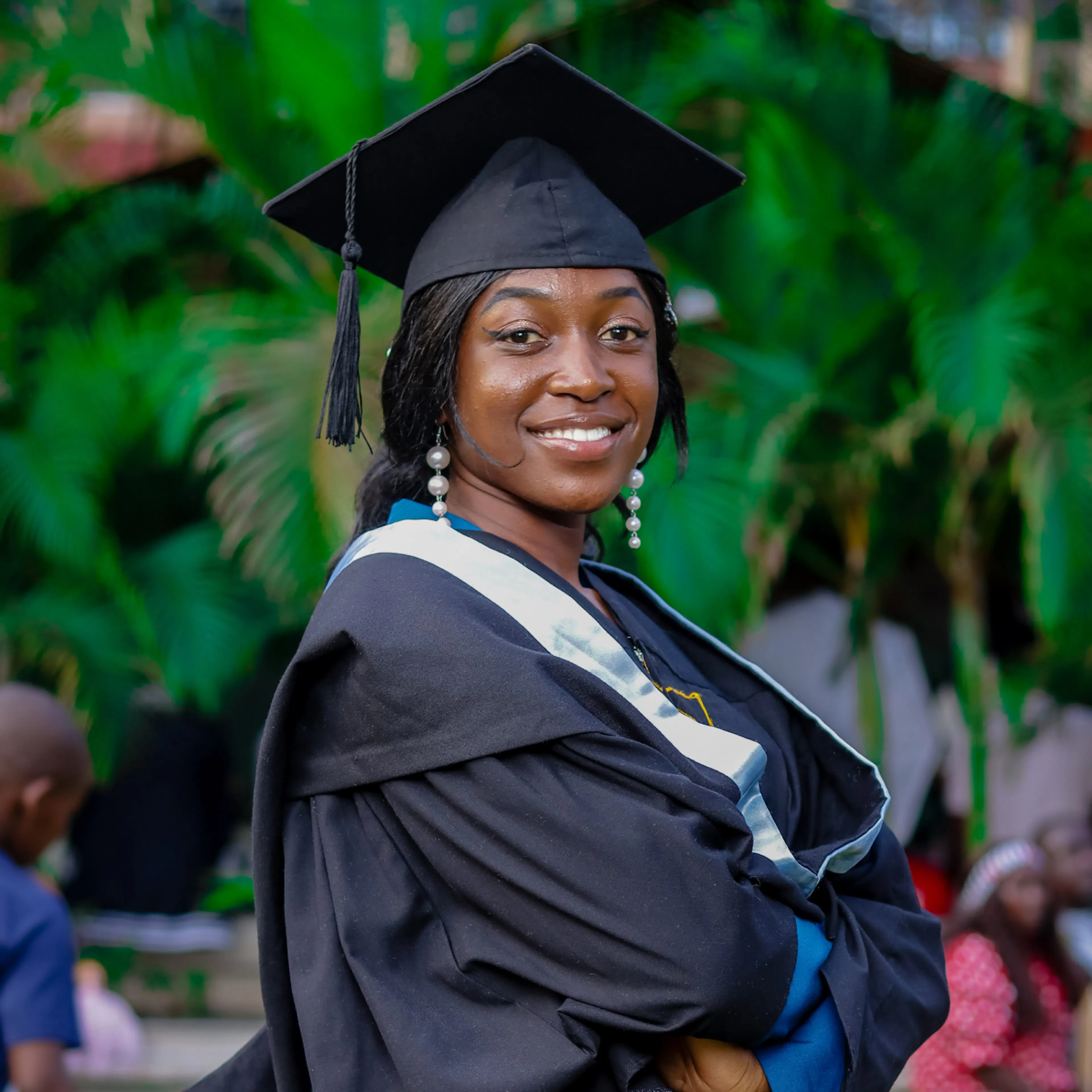 A university graduate in cap and gown smiling outdoors on graduation day
