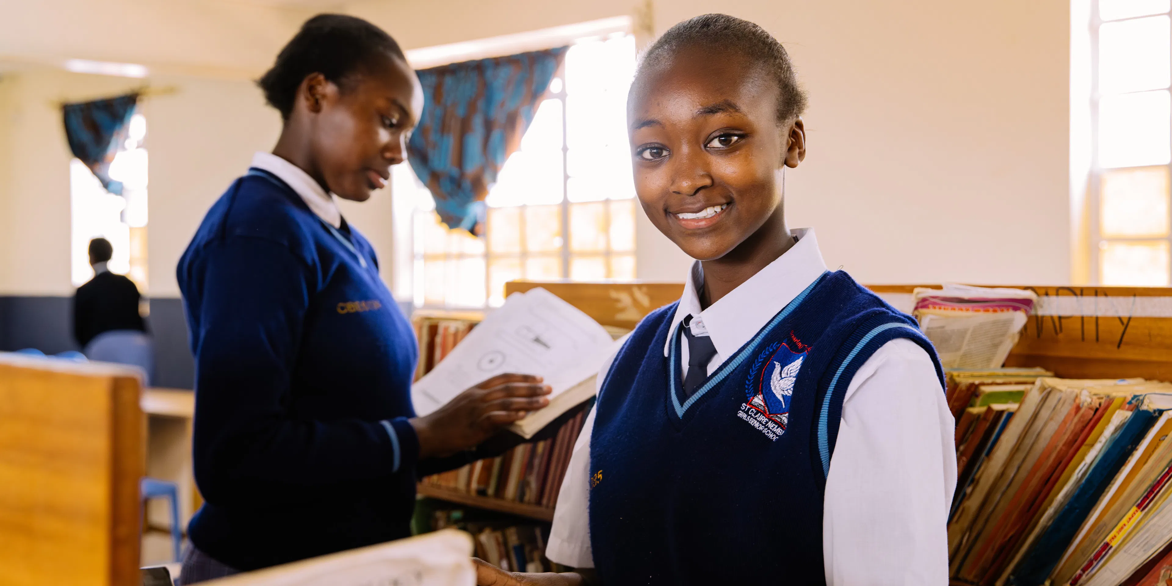 Student holding an open book in a school library in Kenya