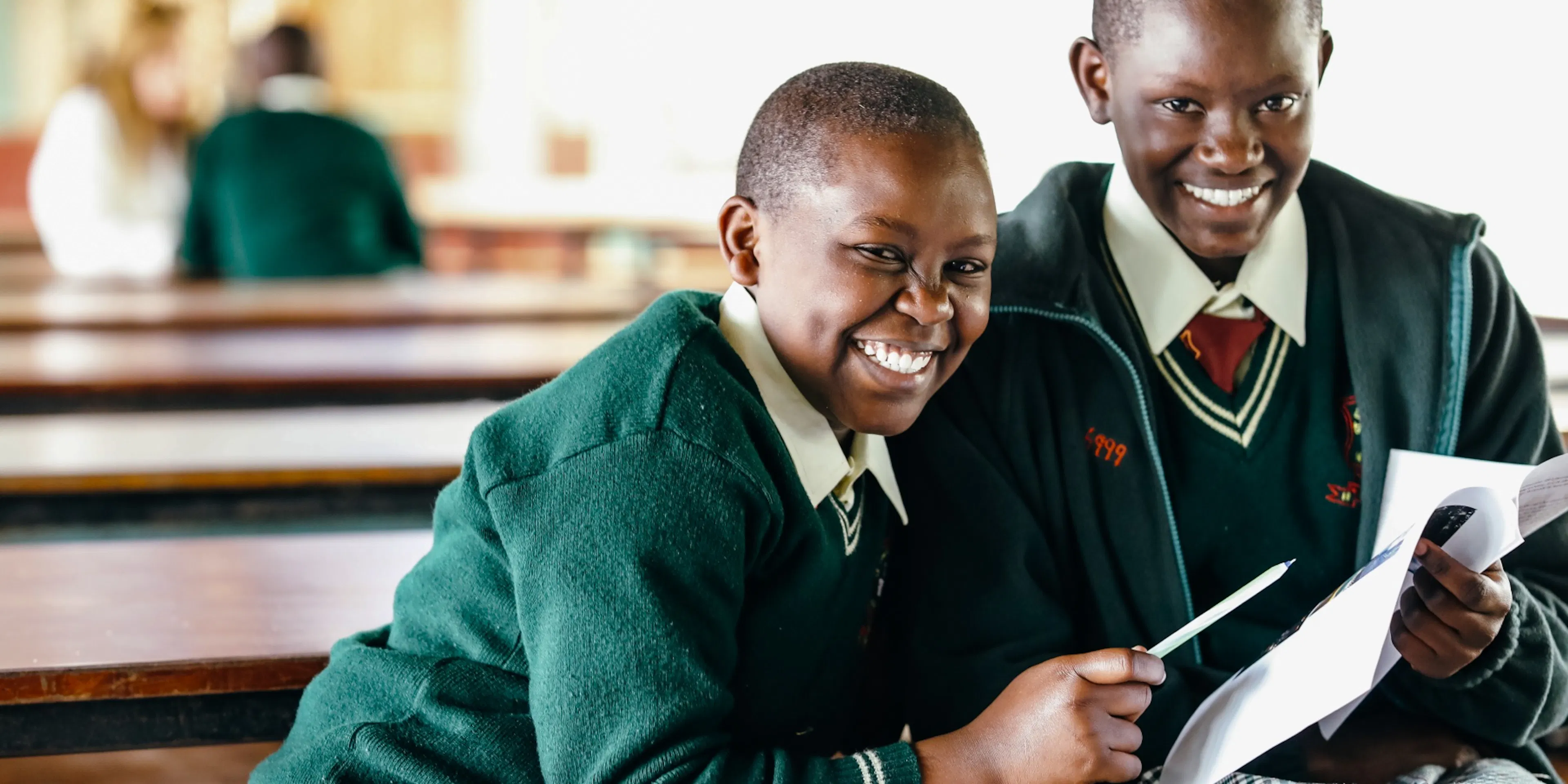 Two students reading together on a classroom bench in Kenya