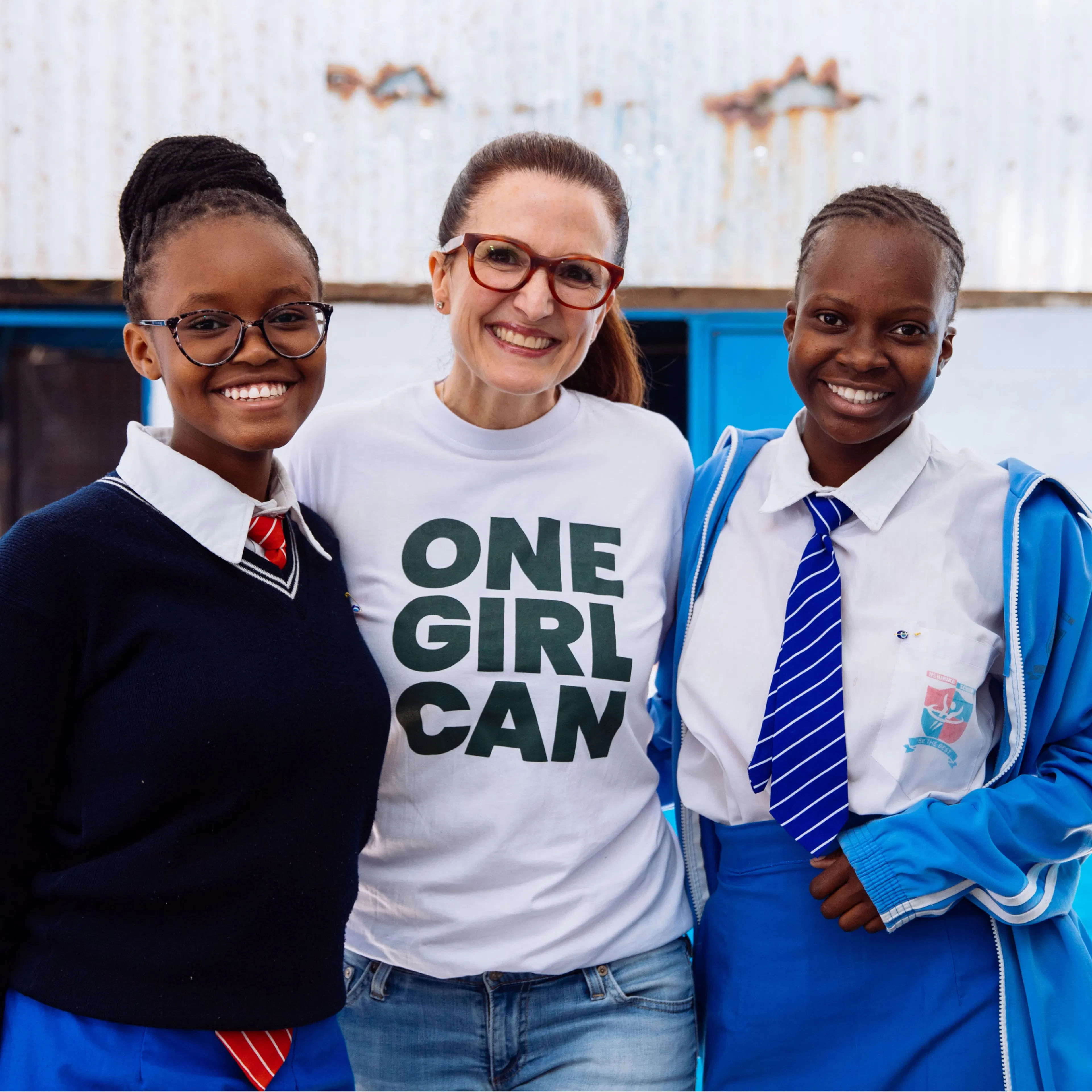 One Girl Can CEO Michelle Sutter standing with two students in Kenya