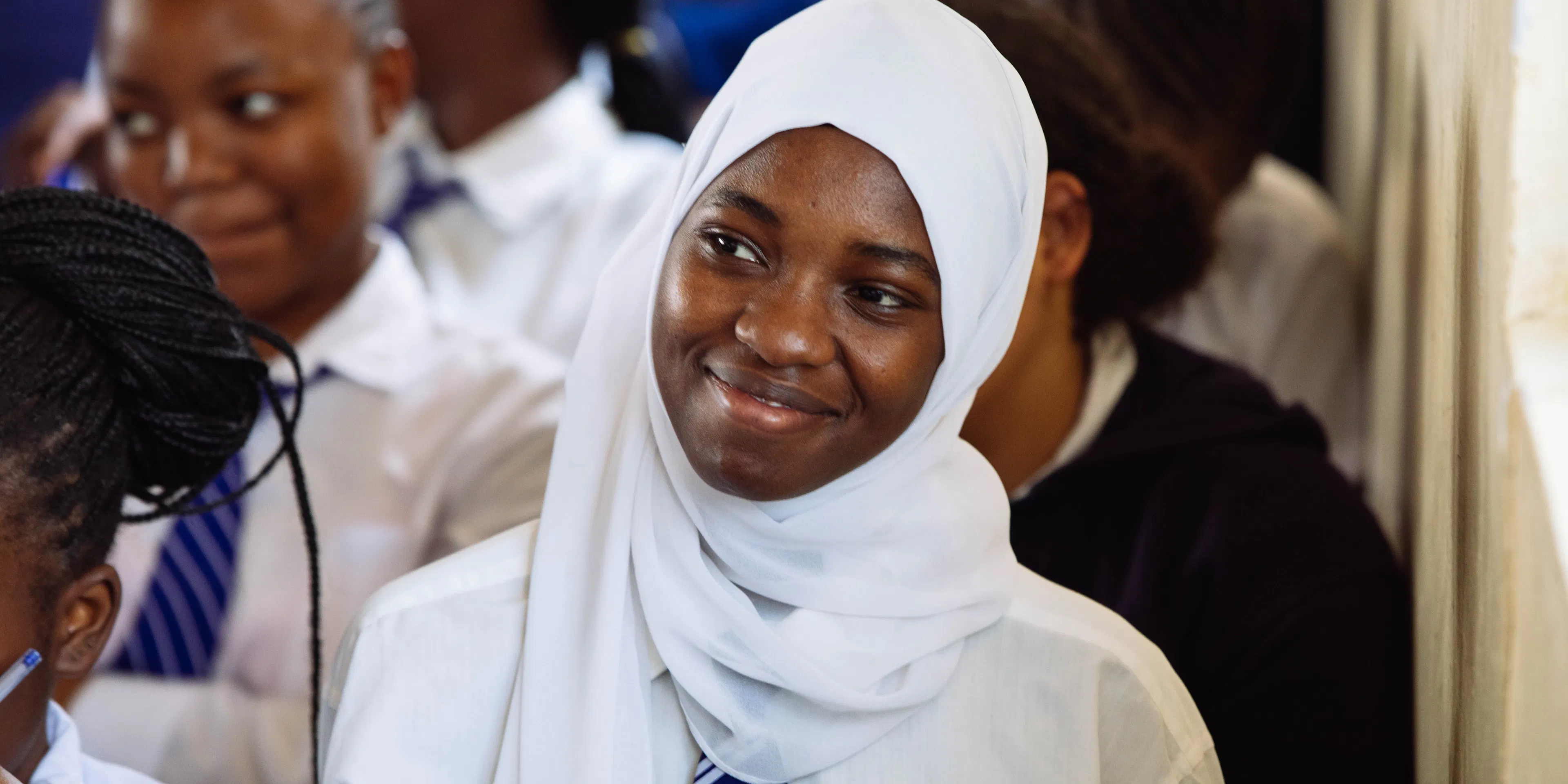 Student in a white hijab smiling among her classmates in Kenya