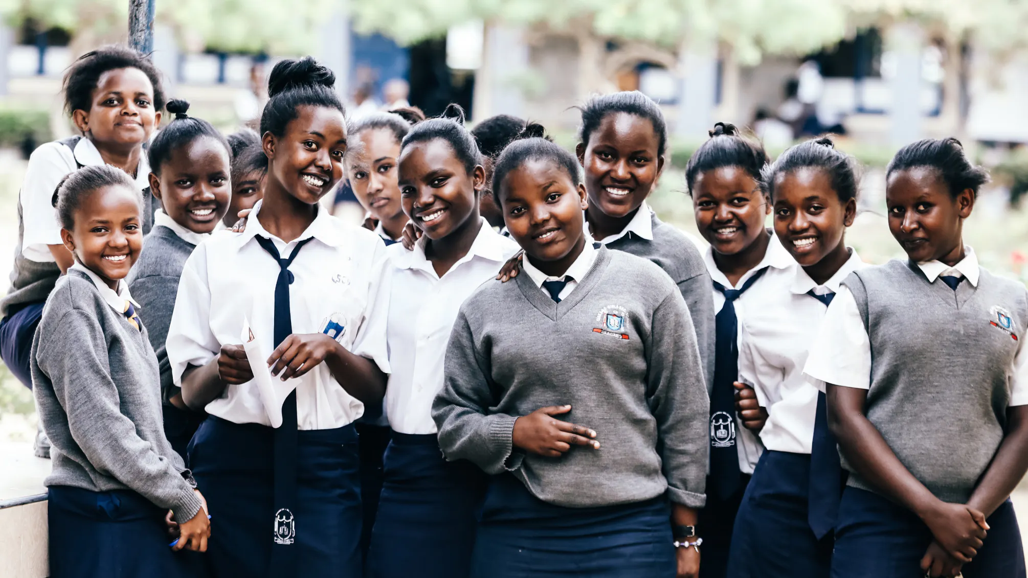 A group of students in navy and grey uniforms smiling together outdoors