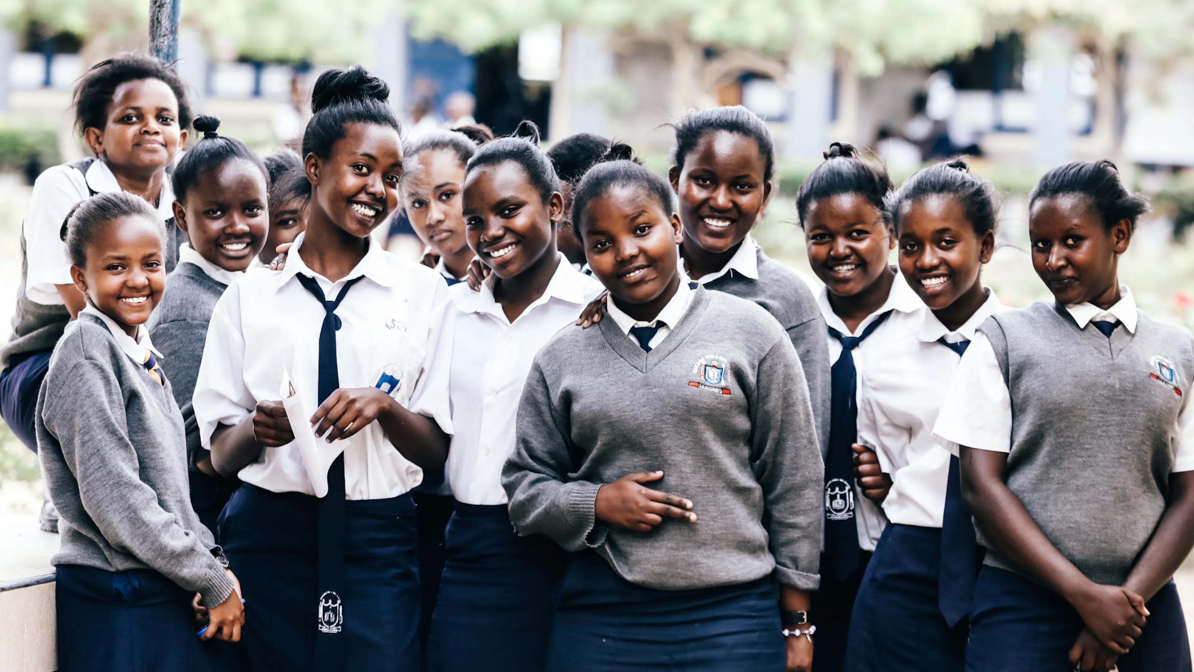 A group of students in navy and grey uniforms smiling together outdoors