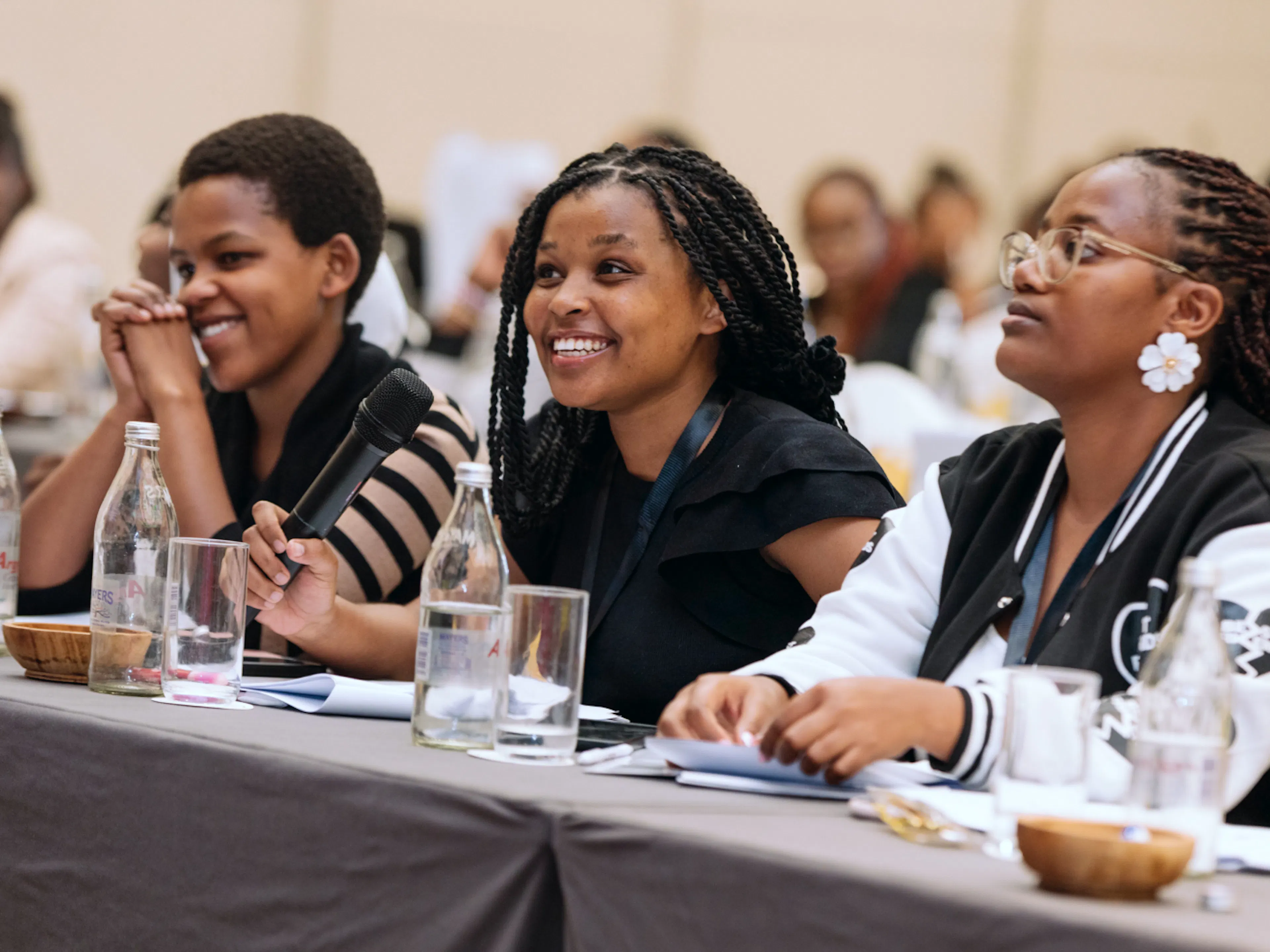 Three young women listening and smiling at a conference table