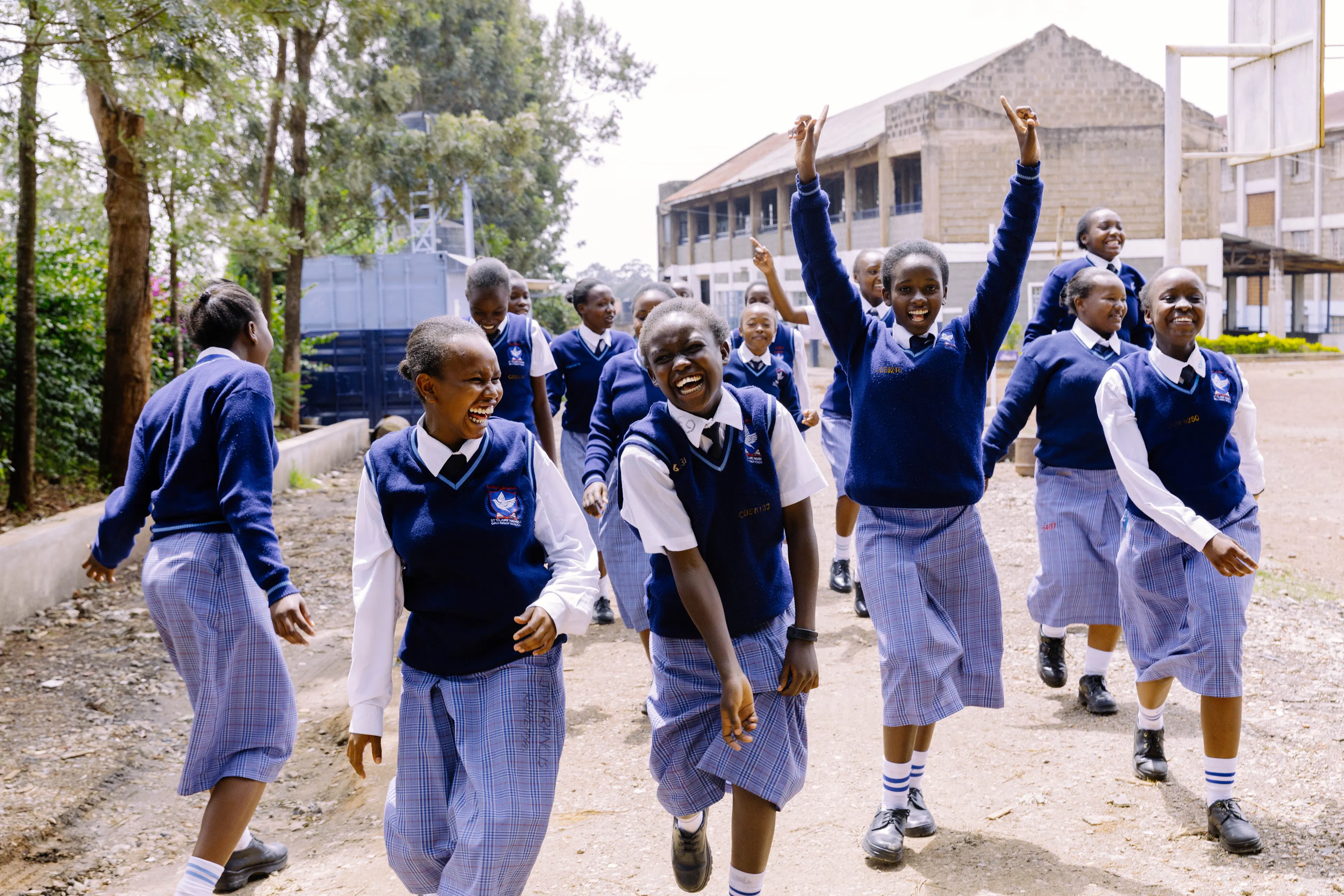 Students walking and cheering together outside their school in Kenya