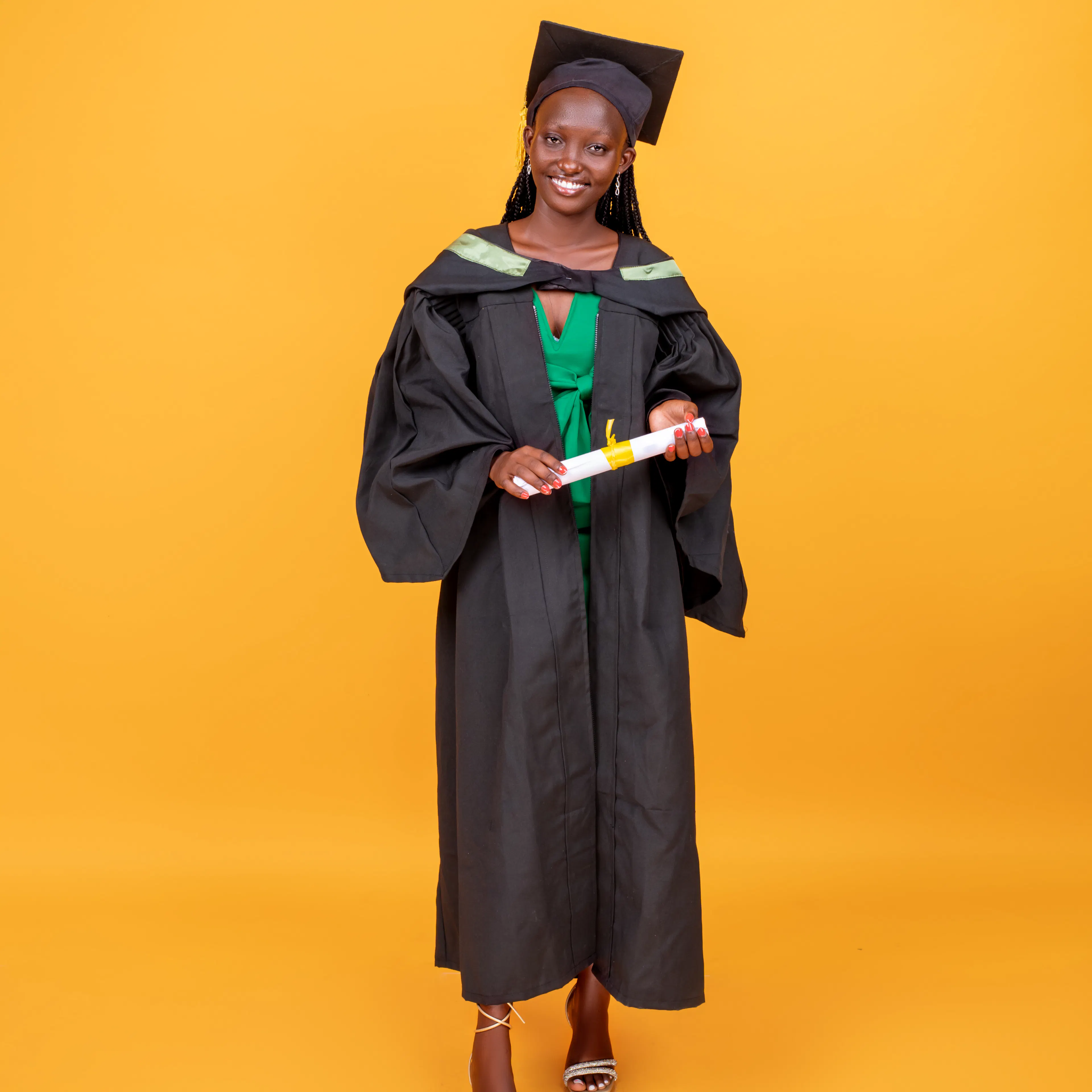 Felistas Nduku in her graduation cap and gown against a yellow backdrop