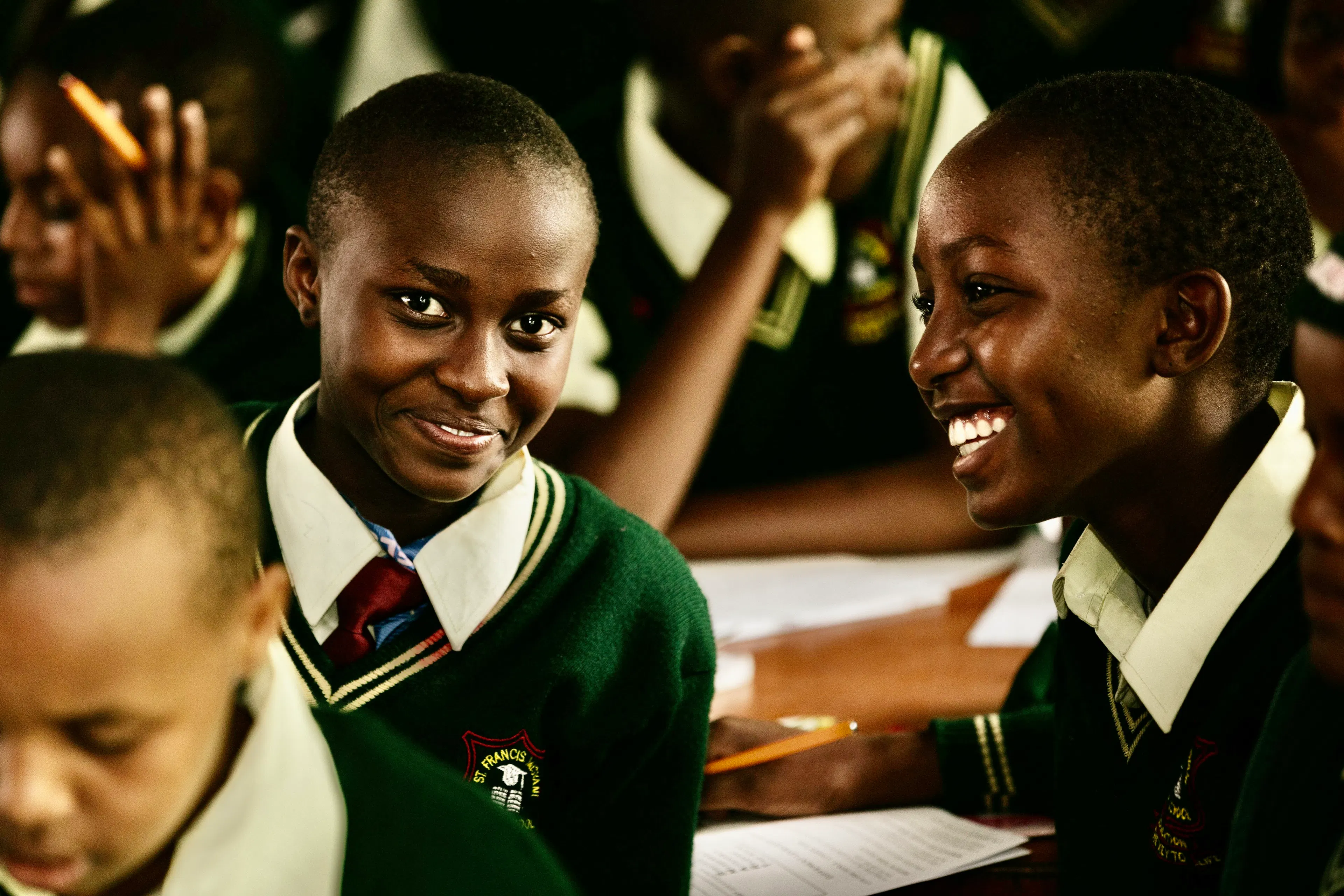 Student in a green school uniform looking up from her desk during a lesson