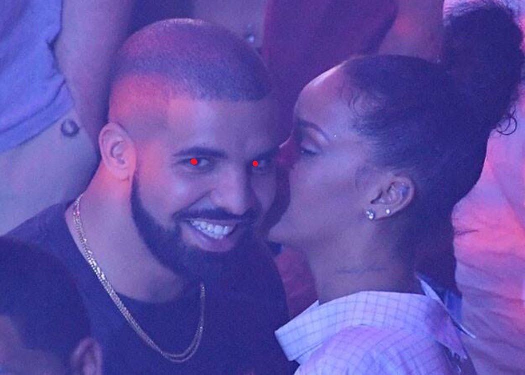 Drake with evil red eyes smiling as Rihanna whispers in his ear