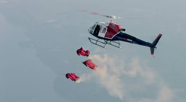 Tre personer hopper ut av helikopter.