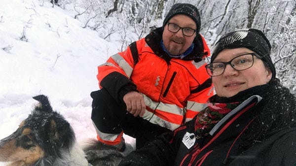 Mann, kone og hund på tur i skogen om vinteren.