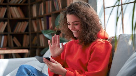 tenåring jente sitter i sofa med smarttelefon