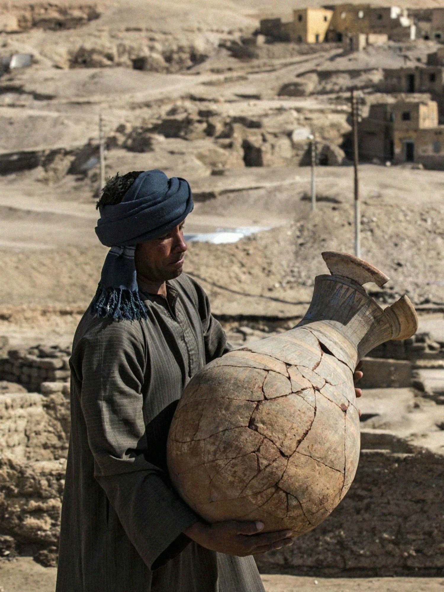 A man carrying a large cracked pot.