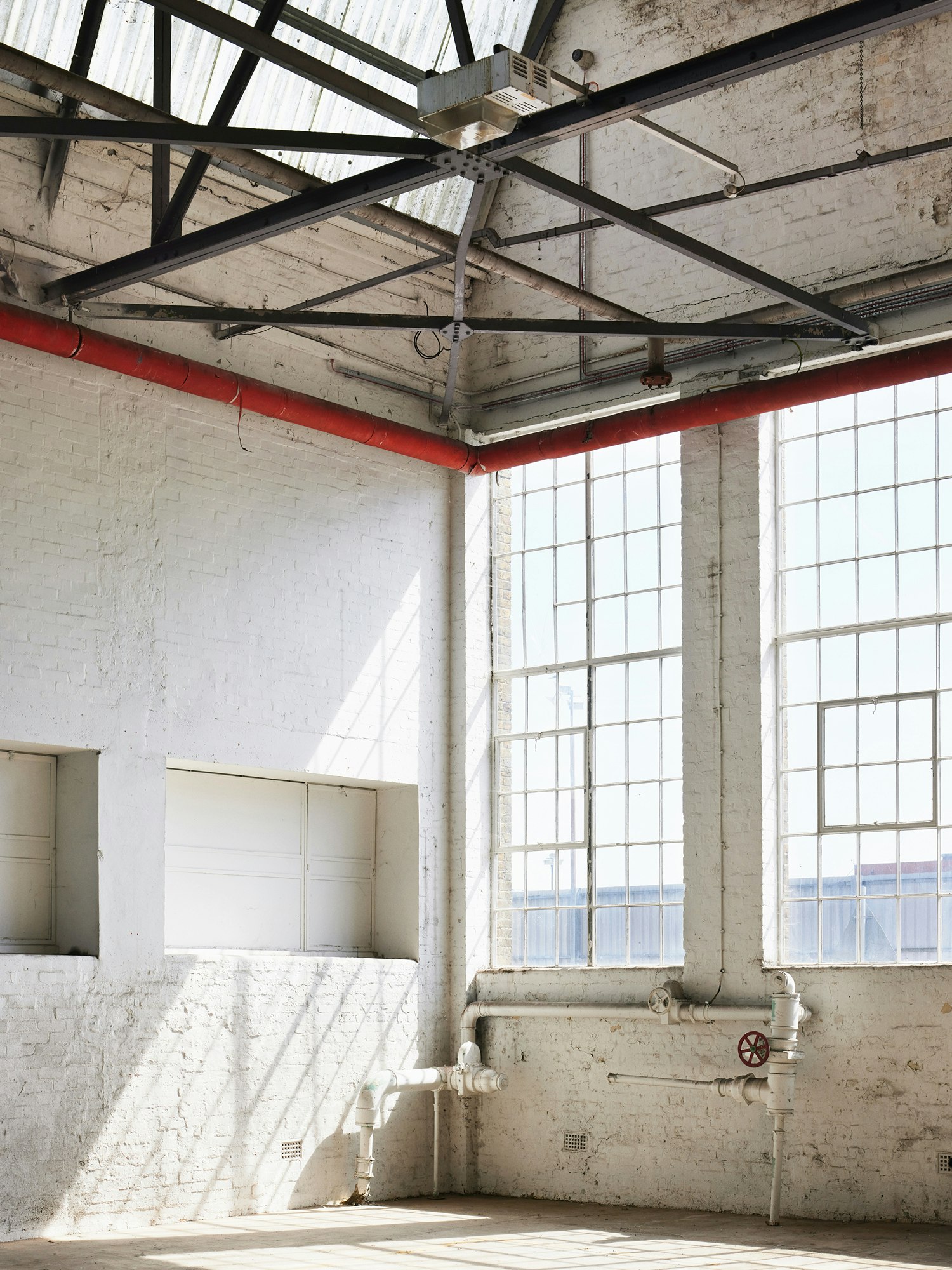 An interior photograph of a room at The Beams, with sunlight streaming through its tall windows.