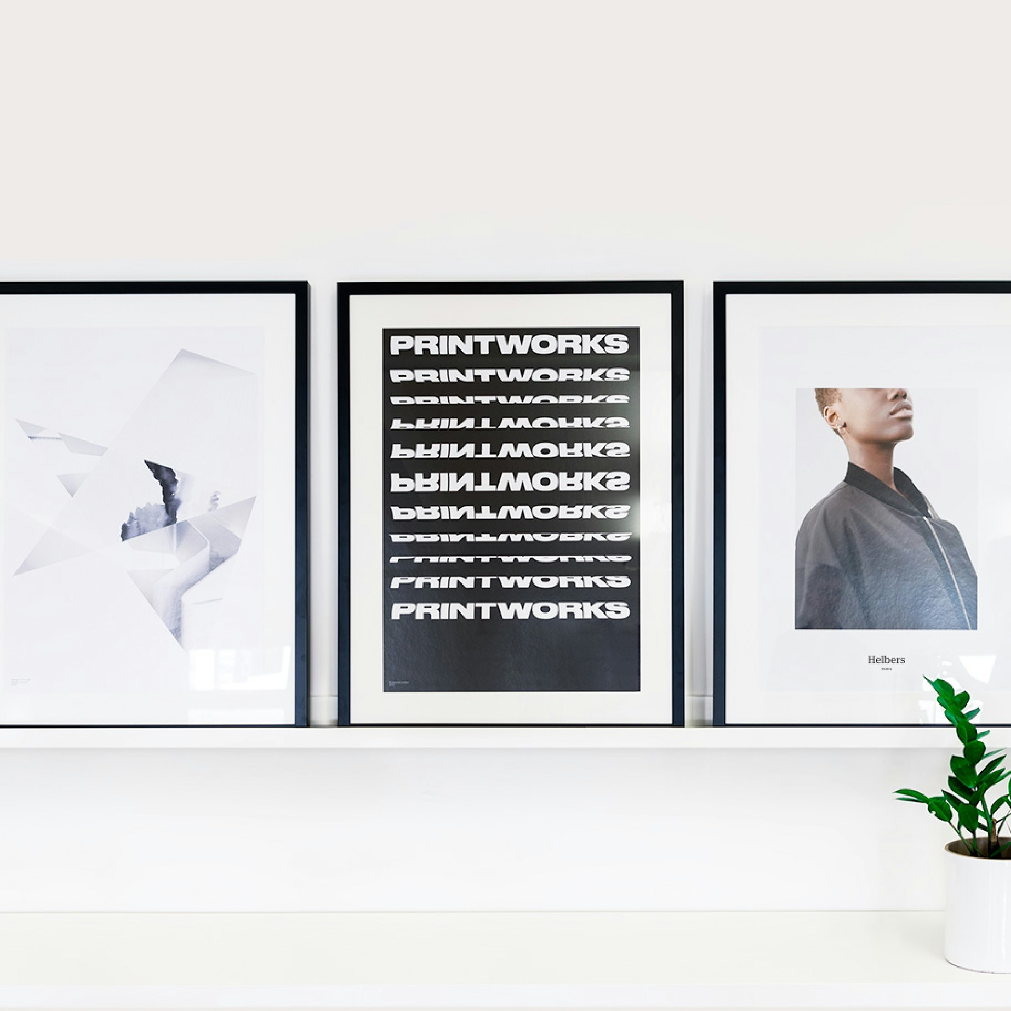 A shelf displaying three framed prints, mounted on a white background.